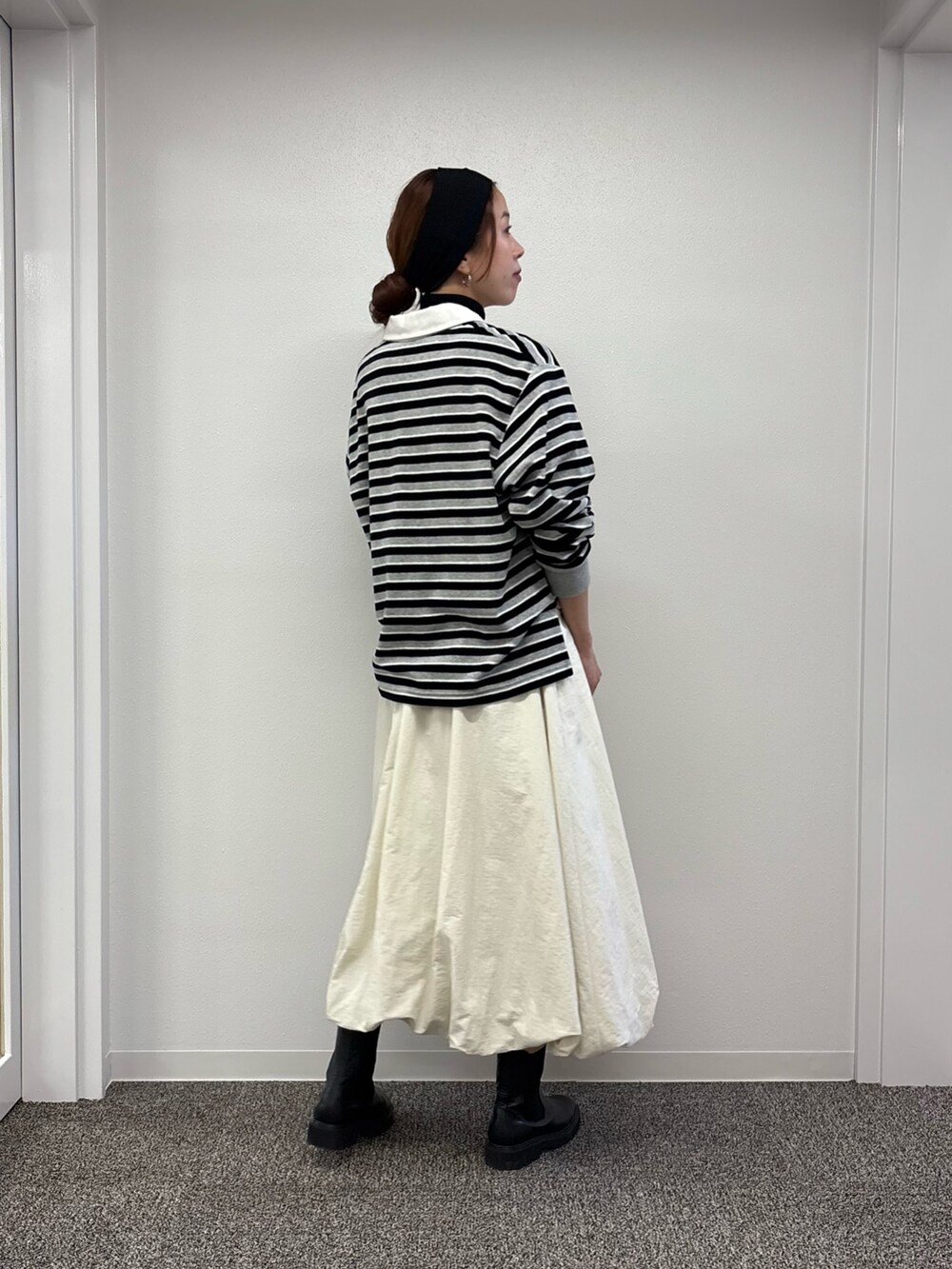 ホワイト系のスカート、ブラック系のニット/セーター、レッド系のTシャツ/カットソーを着用したレディースの秋コーディネートの2枚目の写真