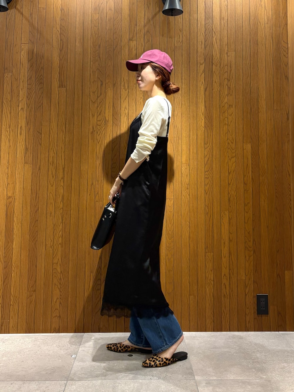 ブラック系のワンピース、ブルー系のデニムパンツ、ブラック系のショルダーバッグを着用したレディースの秋コーディネートの2枚目の写真