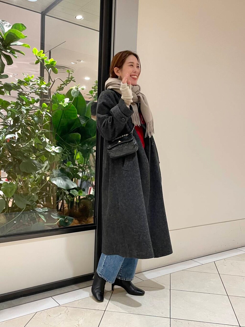 ブルー系のデニムパンツ、ブラック系のショルダーバッグ、レッド系のニット/セーターを着用したレディースの冬コーディネートの3枚目の写真