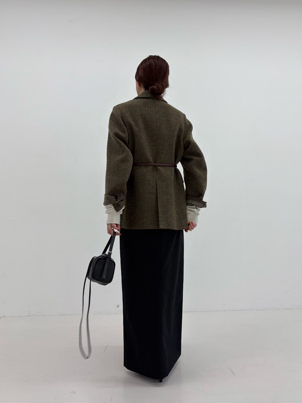 ブラック系のスカート、ブラック系のショルダーバッグ、グリーン系のその他アウターを着用したレディースの秋コーディネートの4枚目の写真