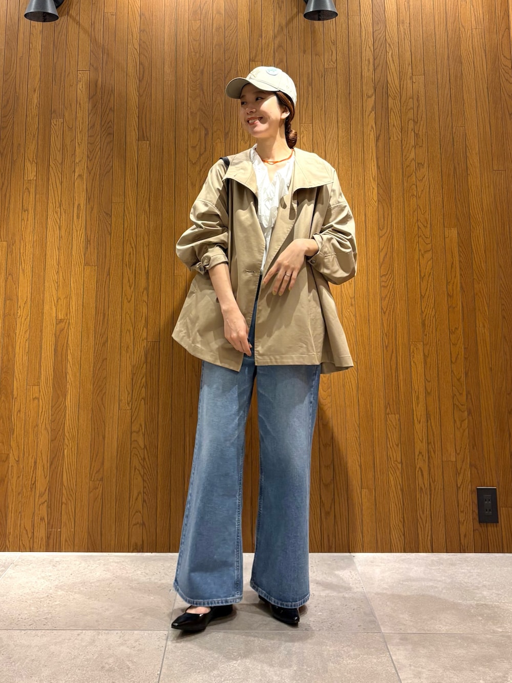 ベージュ系のトレンチコート、ホワイト系のシャツ/ブラウス、ブルー系のデニムパンツを着用したレディースの春コーディネートの4枚目の写真