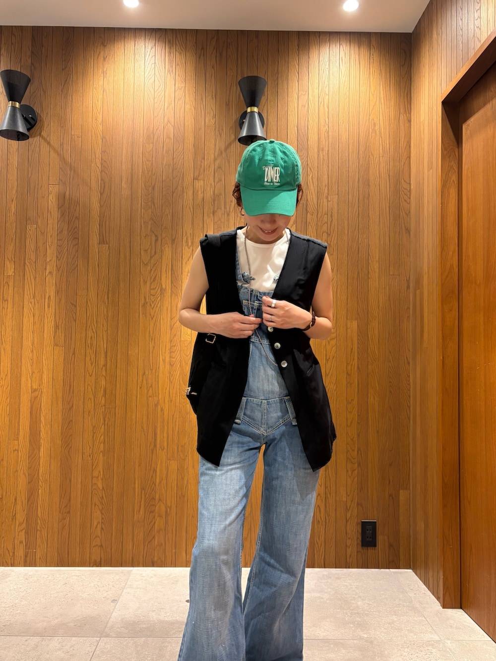 ブラック系のダウンベスト、ブラック系のショルダーバッグ、ホワイト系のTシャツ/カットソーを着用したレディースの夏コーディネートの6枚目の写真