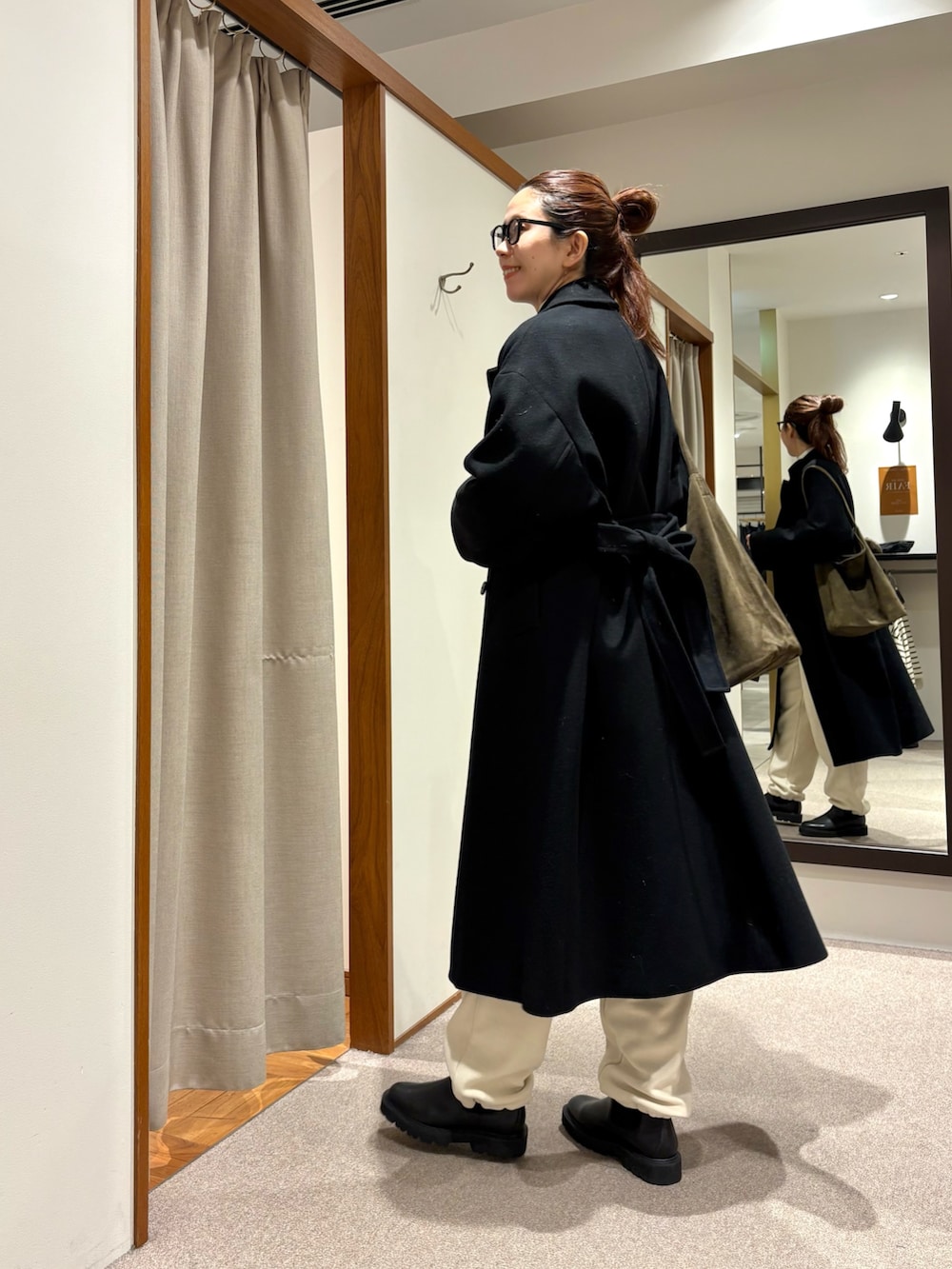 ブラック系のチェスターコート、ホワイト系のその他パンツ、ブラック系のブーツを着用したレディースの冬コーディネートの3枚目の写真