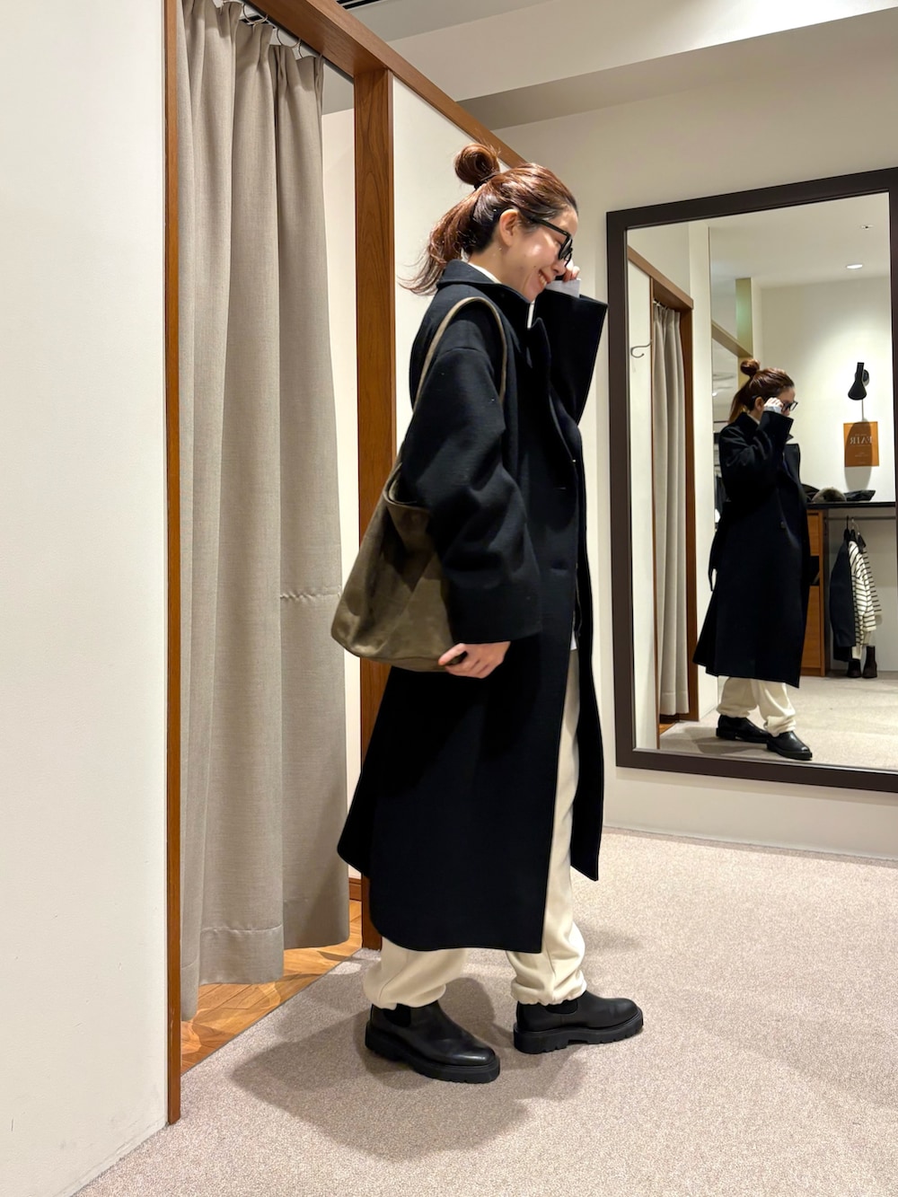 ブラック系のチェスターコート、ホワイト系のその他パンツ、ブラック系のブーツを着用したレディースの冬コーディネートの2枚目の写真