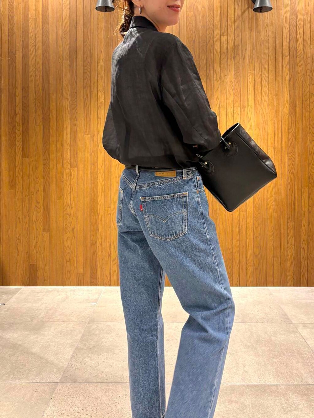 ブラック系のその他アウター、ブルー系のデニムパンツ、ベージュ系のキャップを着用したレディースの春コーディネートの6枚目の写真