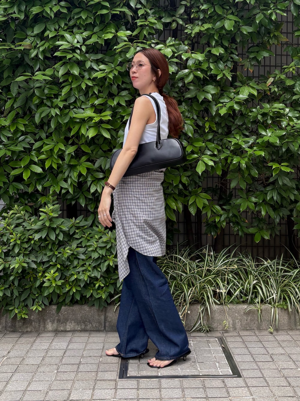 ブルー系のデニムパンツ、ブラック系のショルダーバッグ、ホワイト系のタンクトップを着用したレディースの夏コーディネートの2枚目の写真
