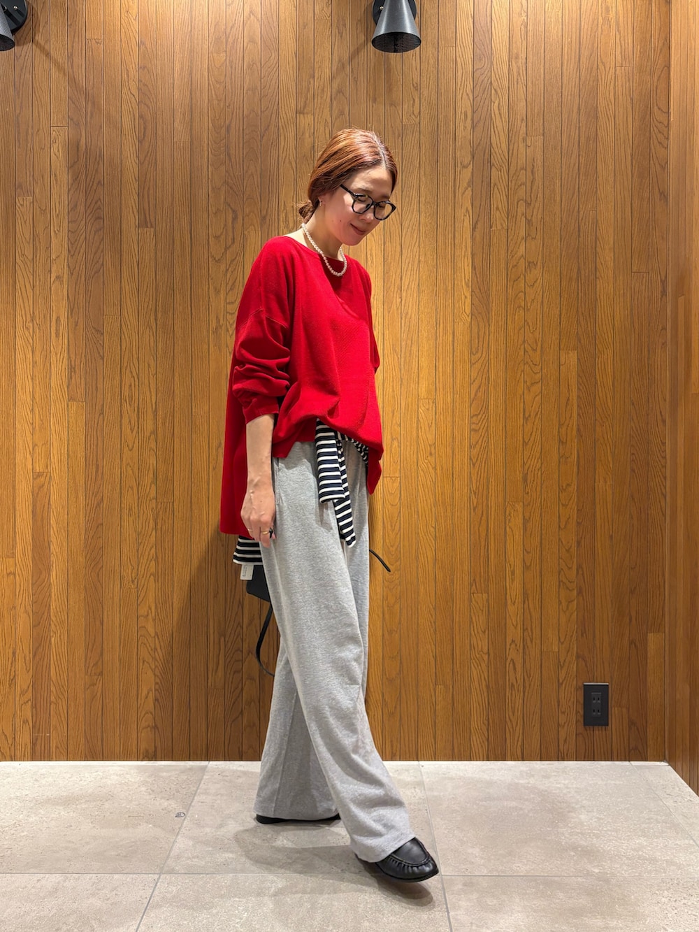レッド系のニット/セーター、ブルー系のTシャツ/カットソー、グレー系のその他パンツを着用したレディースの秋コーディネートの4枚目の写真