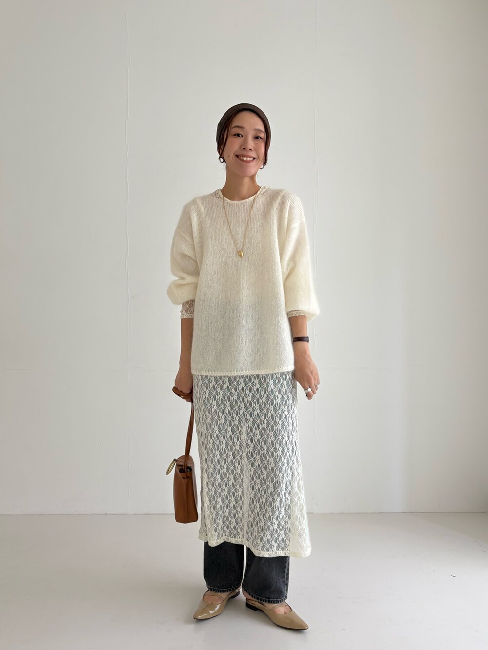 ホワイト系のニット/セーター、ホワイト系のワンピース、ブラック系のデニムパンツを着用したレディースの秋コーディネートの5枚目の写真