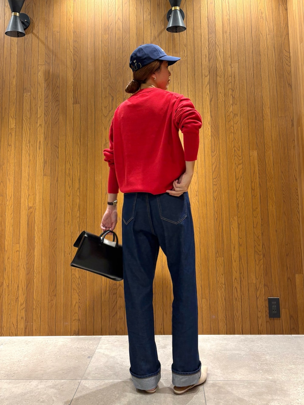 ブルー系のデニムパンツ、レッド系のニット/セーター、ブラック系のハンドバッグを着用したレディースの秋コーディネートの4枚目の写真
