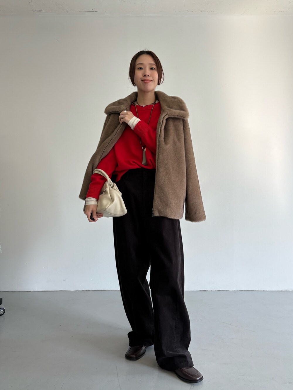 グレー系のその他パンツ、レッド系のニット/セーター、ブラック系のハンドバッグを着用したレディースの冬コーディネートの2枚目の写真