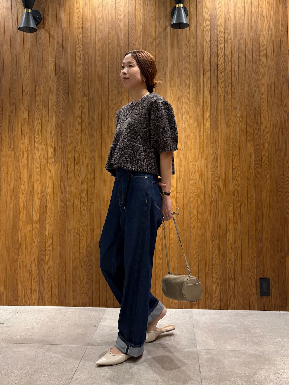 ブルー系のデニムパンツ、ブラウン系のニット/セーター、ベージュ系のハンドバッグを着用したレディースの秋コーディネートの2枚目の写真