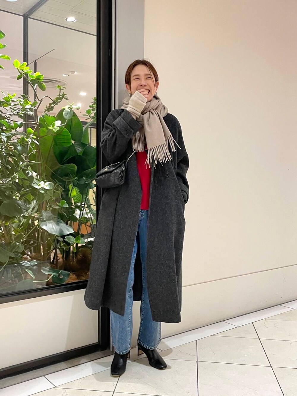 ブルー系のデニムパンツ、ブラック系のショルダーバッグ、レッド系のニット/セーターを着用したレディースの冬コーディネートの2枚目の写真