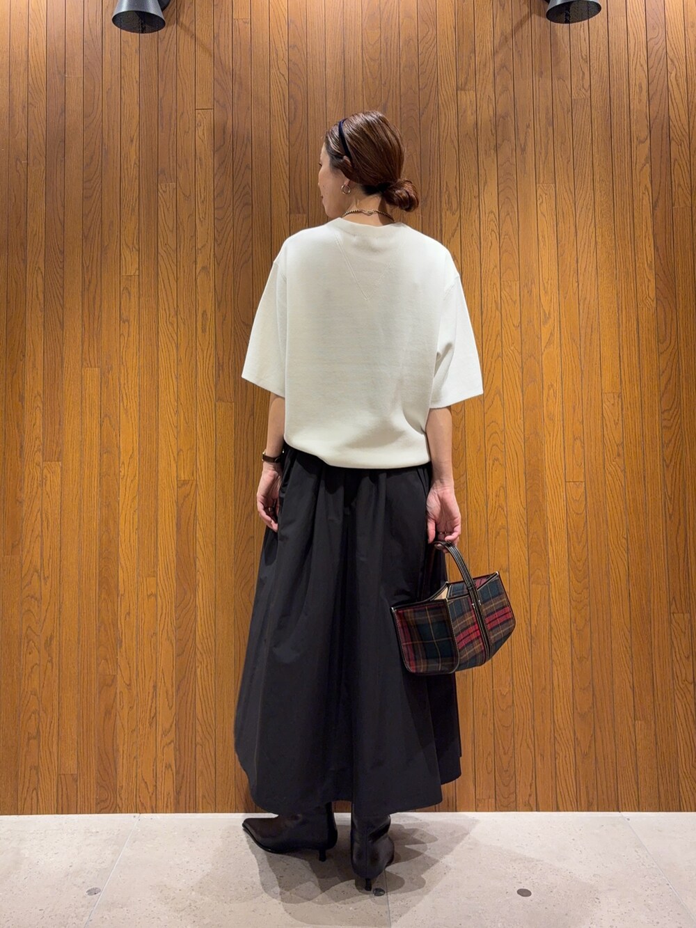 ホワイト系のニット/セーター、ブラック系のブーツ、ブラック系のスカートを着用したレディースの秋コーディネートの2枚目の写真