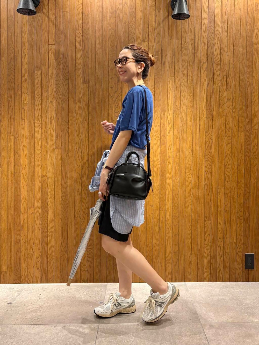 ブルー系のシャツ/ブラウス、シルバー系のスニーカー、ブラック系のショルダーバッグを着用したレディースの夏コーディネートの2枚目の写真