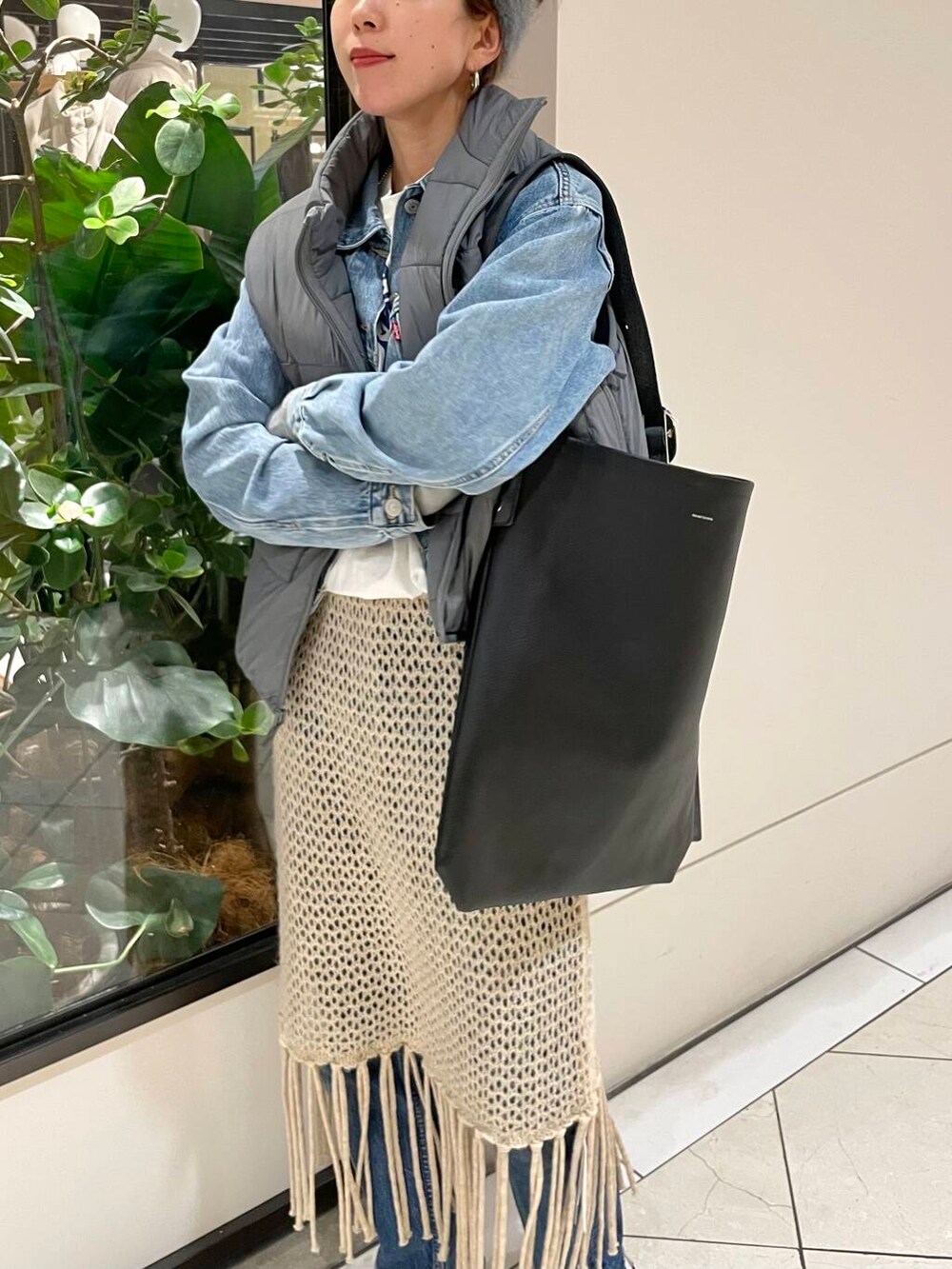 ベージュ系のスカート、ホワイト系のTシャツ/カットソー、グレー系のダウンベストを着用したレディースの冬コーディネートの6枚目の写真