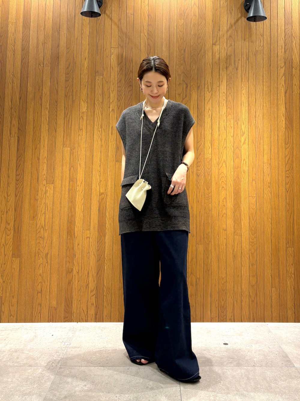 ブラック系のデニムパンツ、ブラック系のニット/セーター、ホワイト系のポーチを着用したレディースの夏コーディネートの6枚目の写真