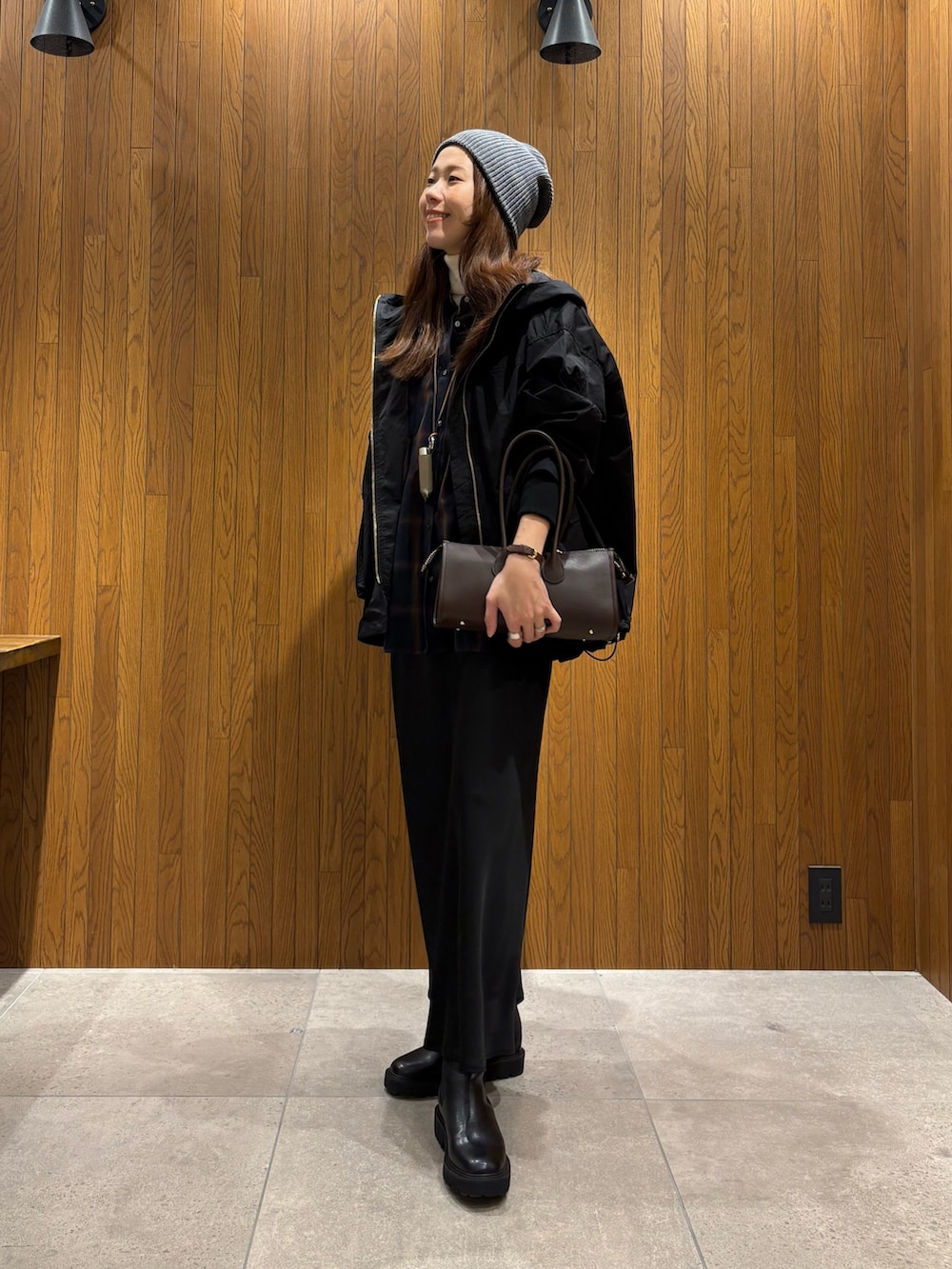 ブラック系のマウンテンパーカー、ブルー系のシャツ/ブラウス、ブラウン系のショルダーバッグを着用したレディースの冬コーディネートの2枚目の写真