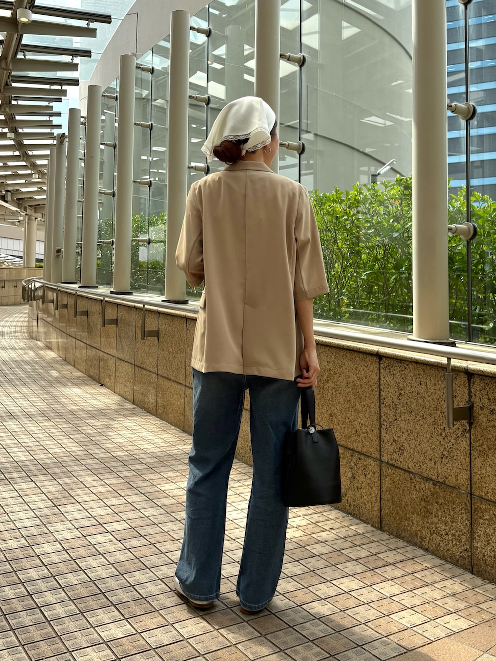 ブルー系のデニムパンツ、ベージュ系のその他アウター、ブラック系のハンドバッグを着用したレディースの春コーディネートの3枚目の写真