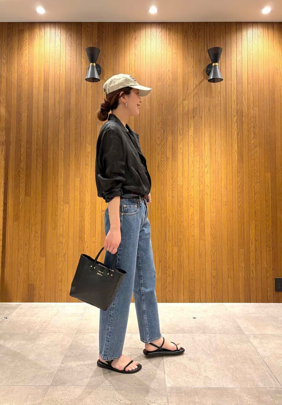 ブラック系のその他アウター、ブルー系のデニムパンツ、ベージュ系のキャップを着用したレディースの春コーディネートの2枚目の写真