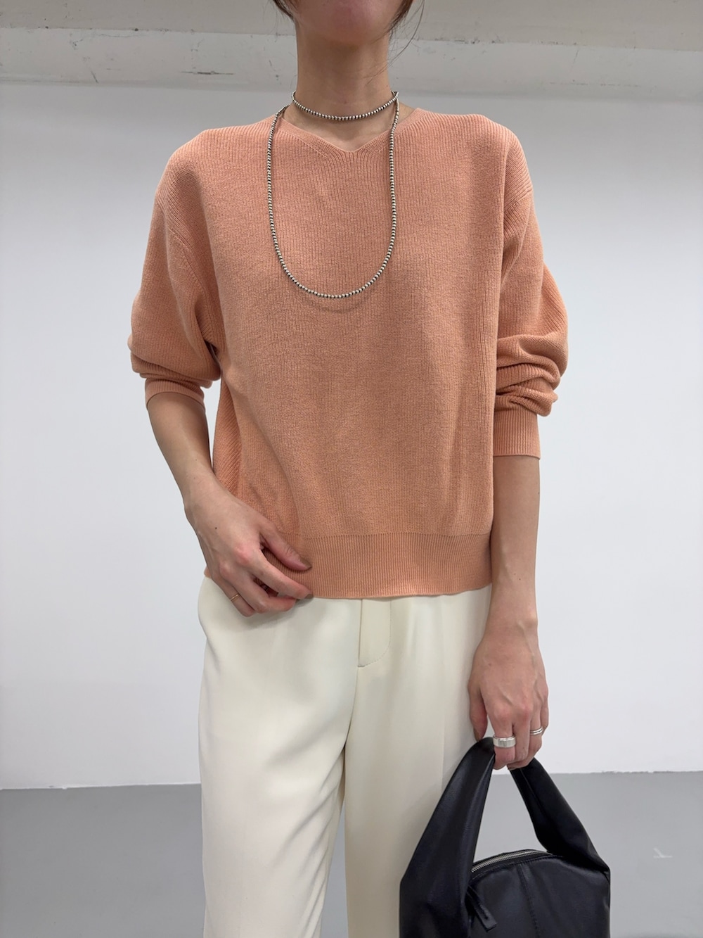 ピンク系のニット/セーター、ブラック系のハンドバッグ、ホワイト系のその他シューズを着用したレディースの冬コーディネートの4枚目の写真