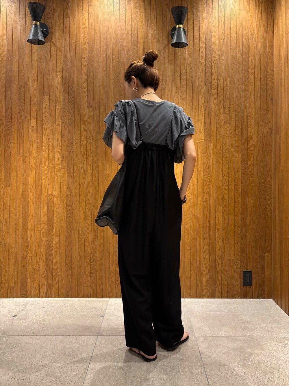 ブラック系のサロペット/オーバーオール、ブルー系のTシャツ/カットソー、ブラック系のサンダルを着用したレディースの夏コーディネートの4枚目の写真