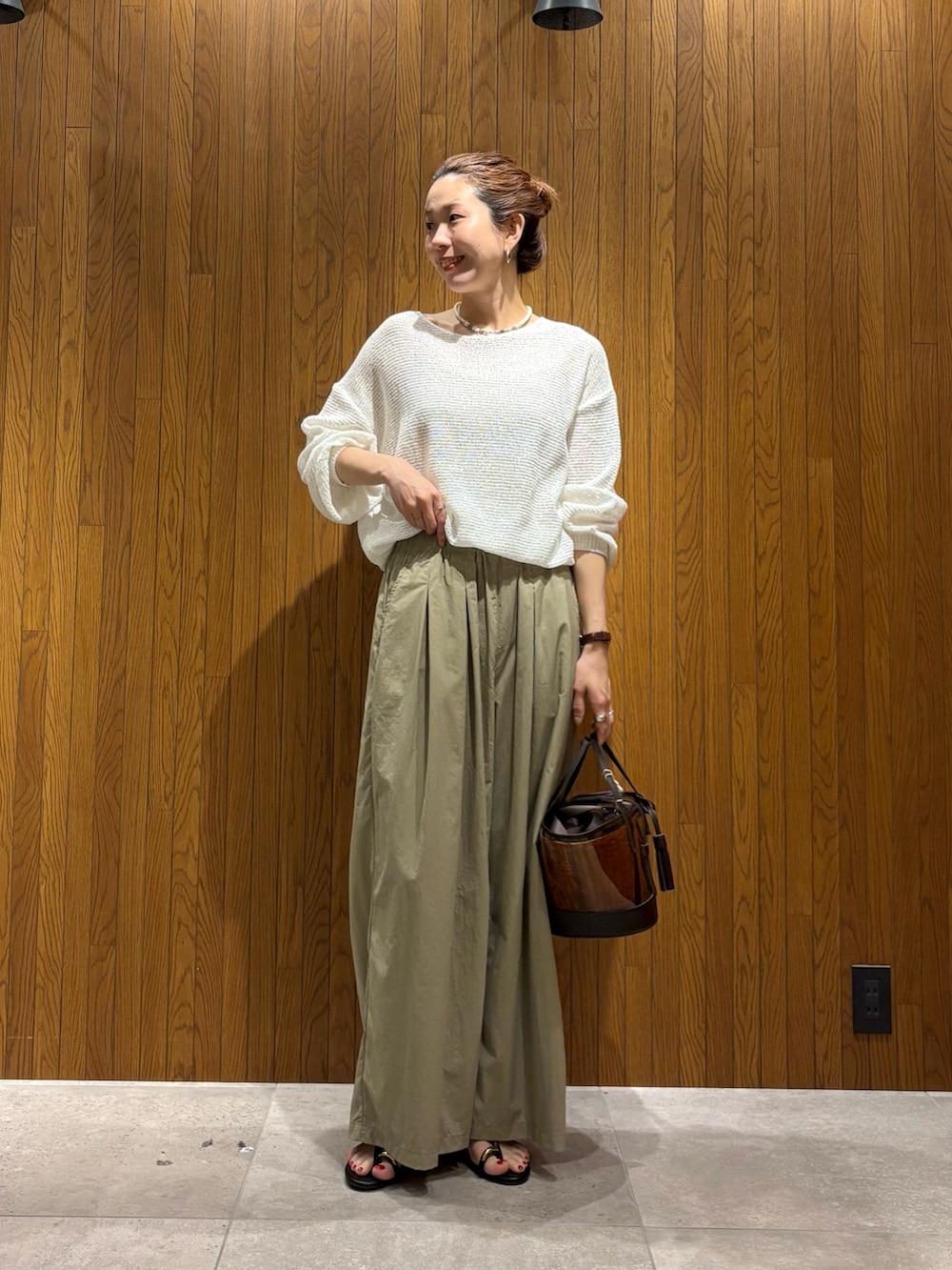 ホワイト系のニット/セーター、ベージュ系のその他パンツ、ブラウン系のかごバッグを着用したレディースの春コーディネートの5枚目の写真