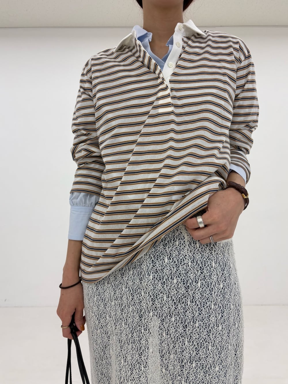 ホワイト系のスカート、ベージュ系のトレンチコート、ホワイト系のスニーカーを着用したレディースの春コーディネートの6枚目の写真