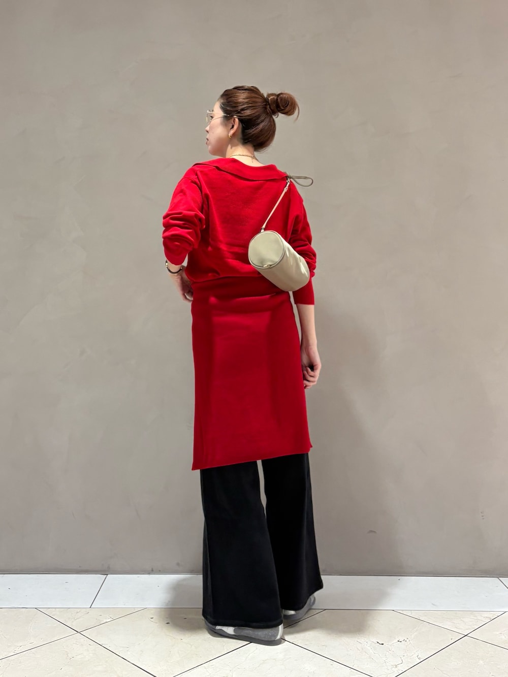 レッド系のニット/セーター、ブラック系のデニムパンツ、グレー系のスニーカーを着用したレディースの秋コーディネートの3枚目の写真