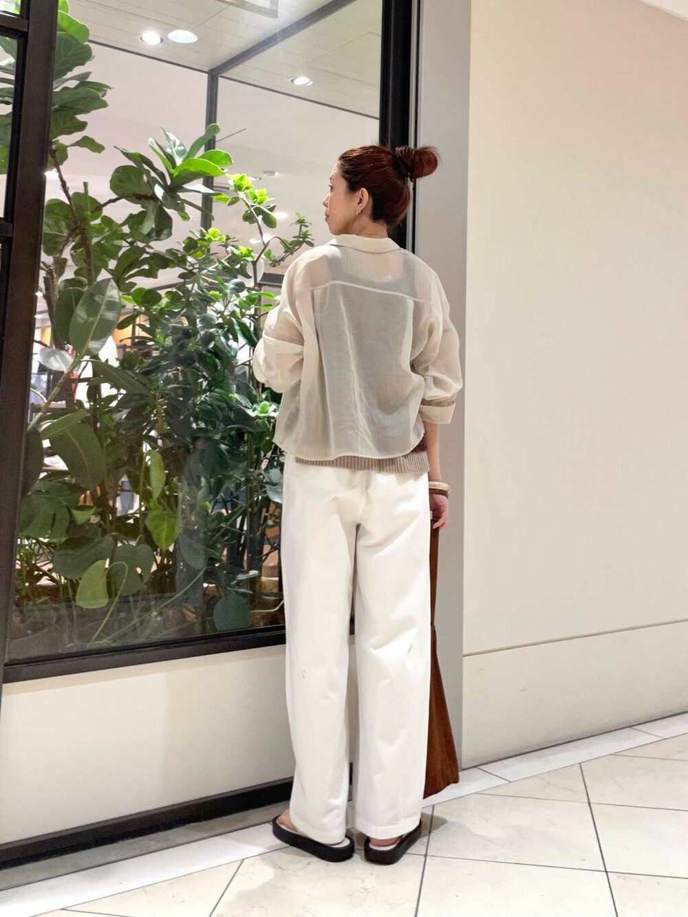 イエロー系のニット/セーター、ホワイト系のその他パンツ、ブラウン系のキャミソールを着用したレディースの春コーディネートの3枚目の写真