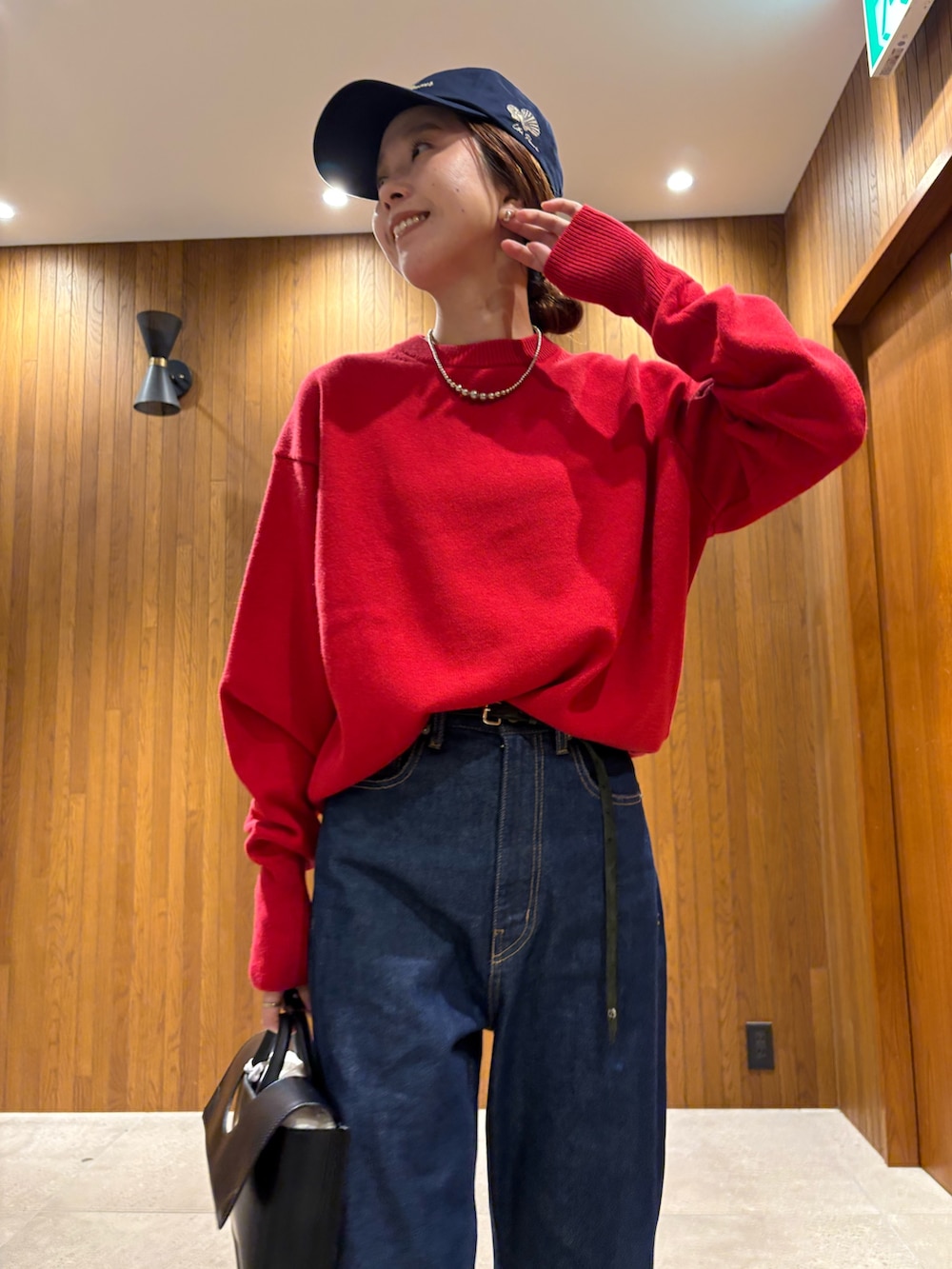 ブルー系のデニムパンツ、レッド系のニット/セーター、ブラック系のハンドバッグを着用したレディースの秋コーディネートの7枚目の写真