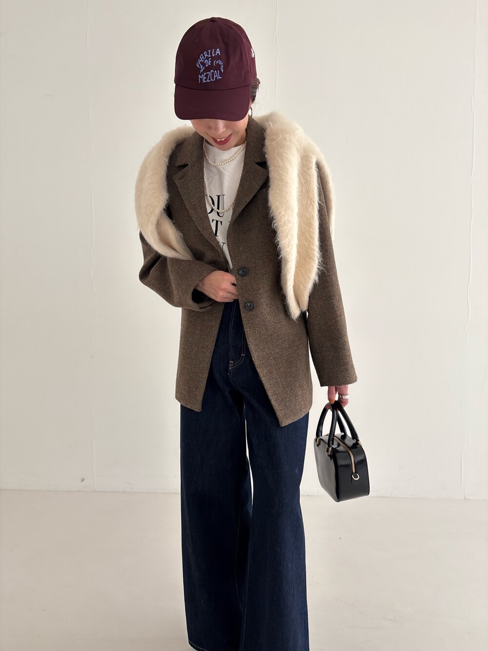 ブルー系のデニムパンツ、ブラック系のローファー、ブラック系のショルダーバッグを着用したレディースの秋コーディネートの7枚目の写真