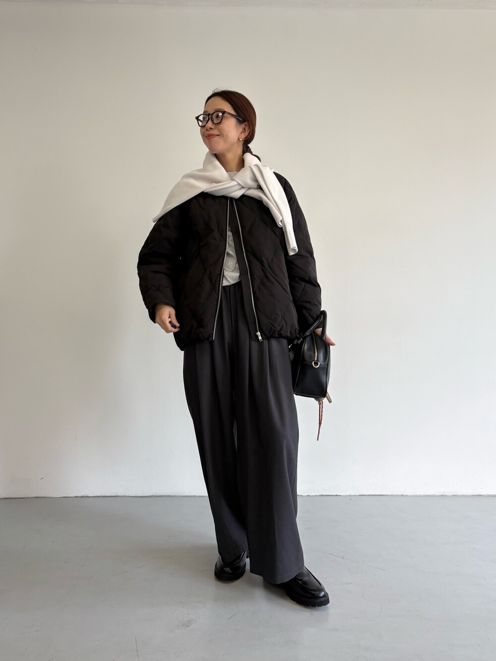 ブラック系のダウンジャケット/コート、グレー系のその他パンツ、ブラック系のローファーを着用したレディースの冬コーディネートの2枚目の写真