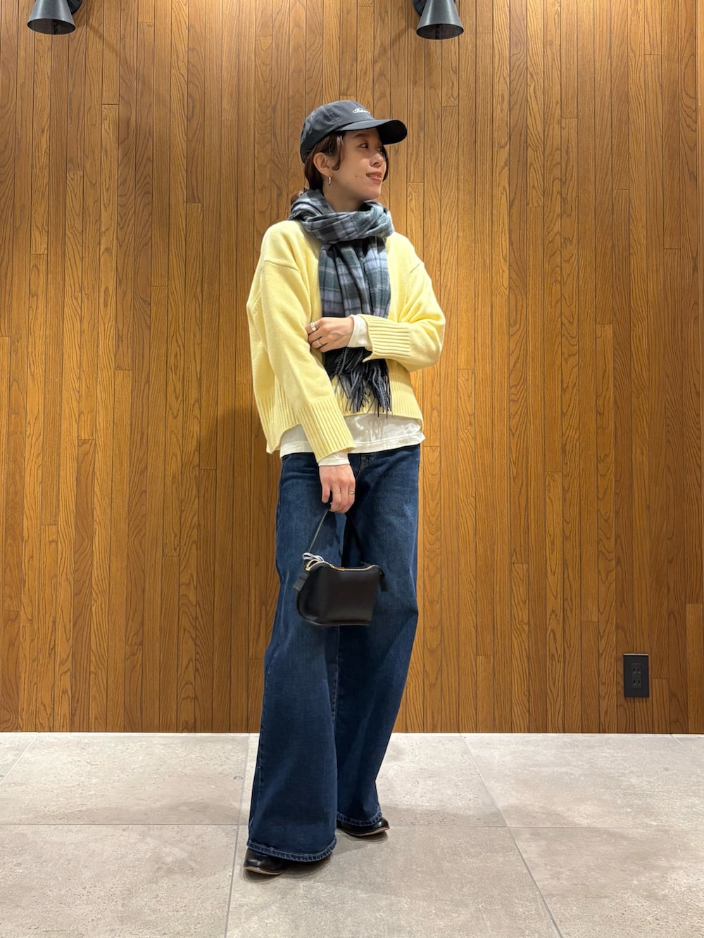 グレー系のその他アウター、イエロー系のニット/セーター、ブルー系のデニムパンツを着用したレディースの冬コーディネートの9枚目の写真