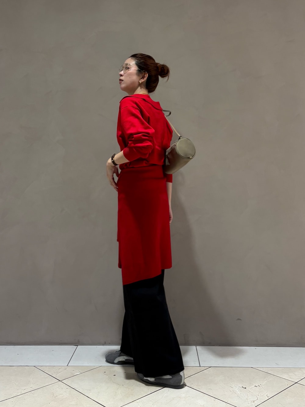 レッド系のニット/セーター、ブラック系のデニムパンツ、グレー系のスニーカーを着用したレディースの秋コーディネートの2枚目の写真