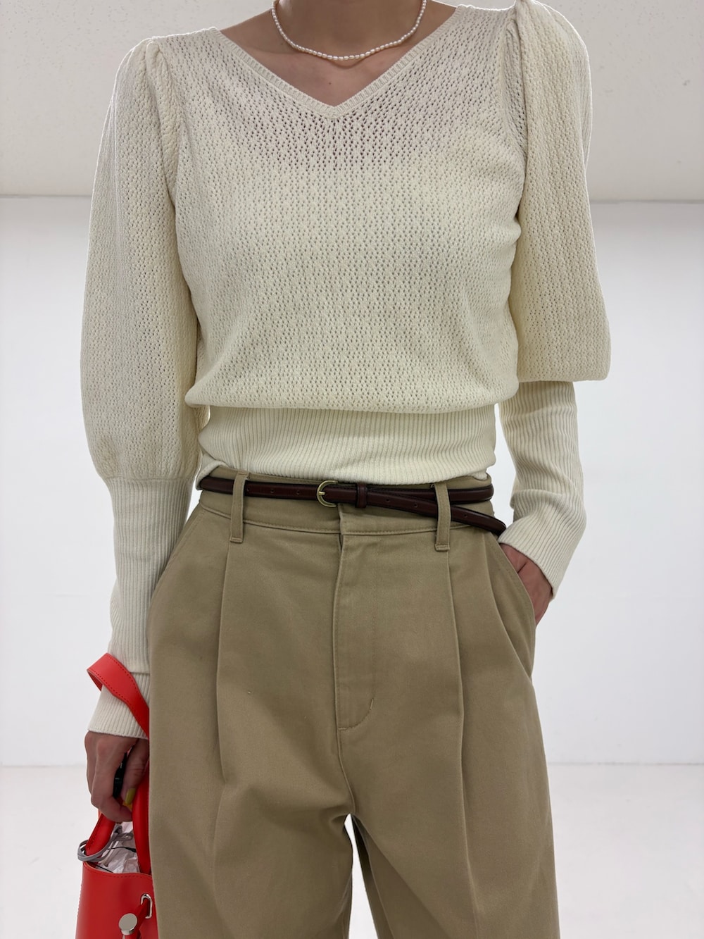 ホワイト系のニット/セーター、ベージュ系のその他パンツ、ブラック系のローファーを着用したレディースの夏コーディネートの7枚目の写真