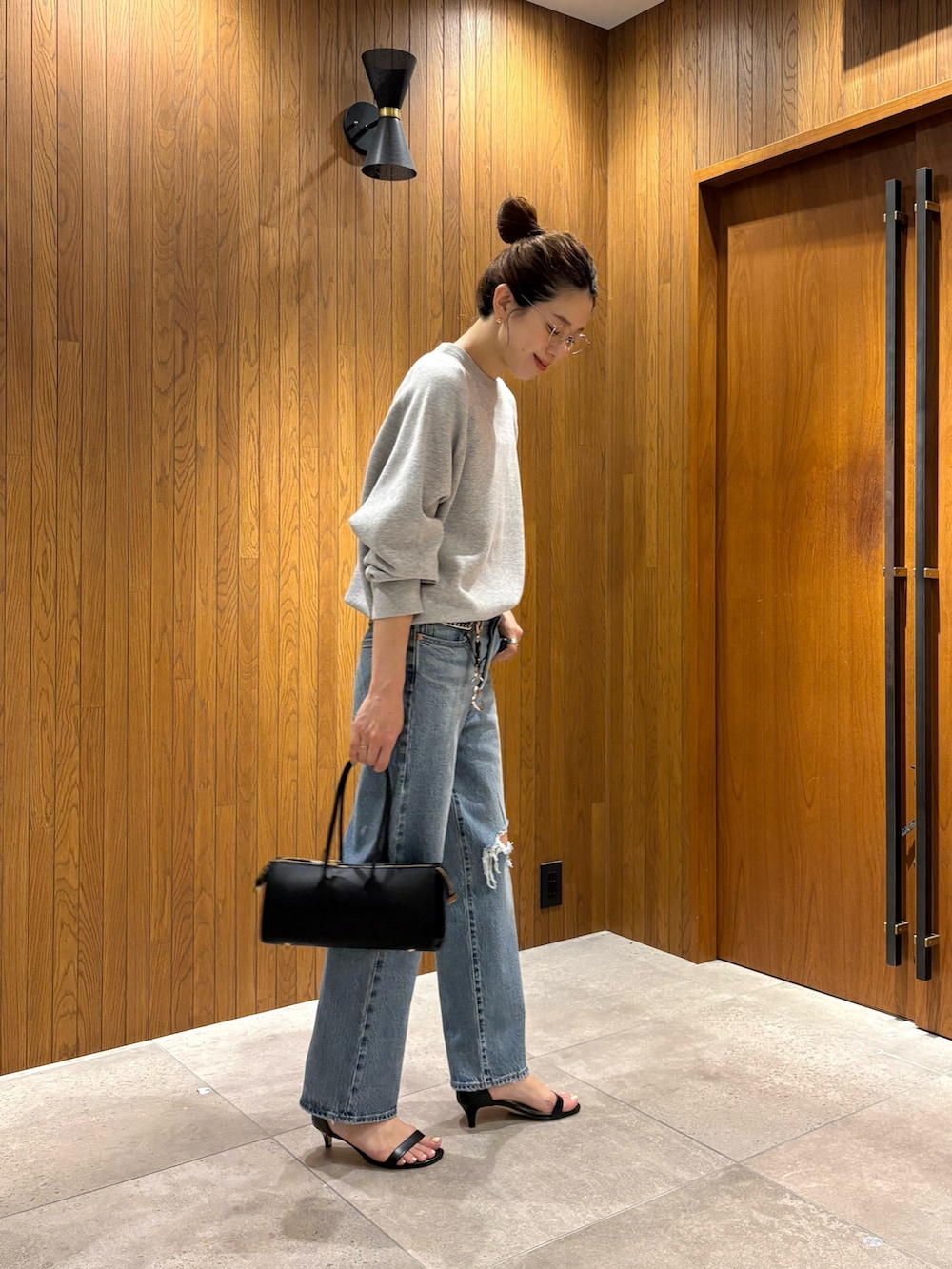 ブルー系のデニムパンツ、グレー系のニット/セーター、ブラック系のショルダーバッグを着用したレディースの秋コーディネートの2枚目の写真