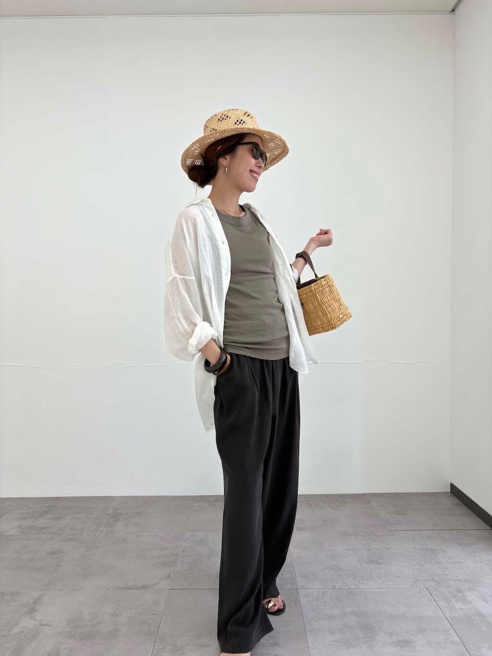 ブラウン系のかごバッグ、ホワイト系のシャツ/ブラウス、ブラック系のサンダルを着用したレディースの夏コーディネートの7枚目の写真