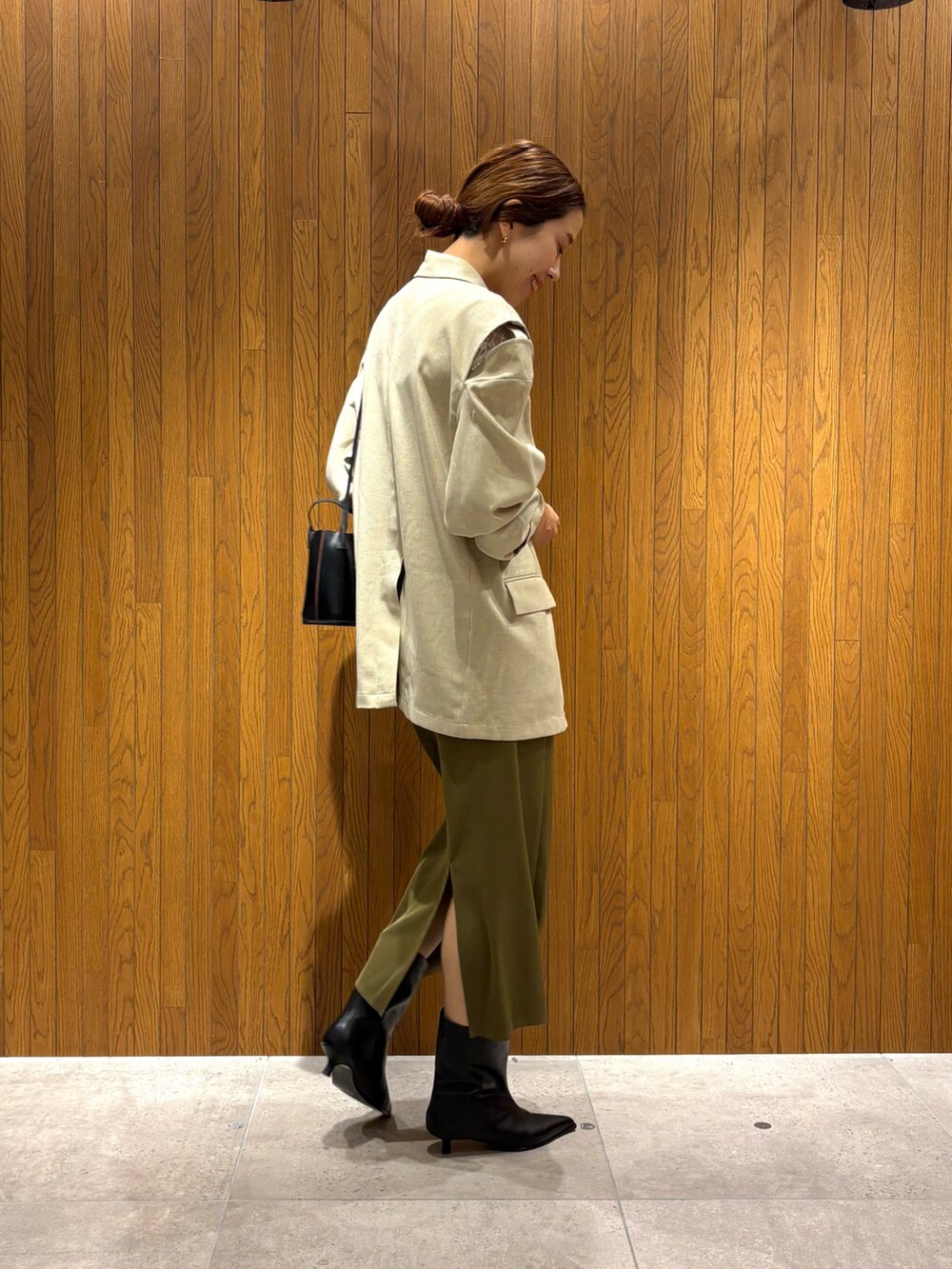 グリーン系のスカート、ブラック系のブーツ、ホワイト系のその他アウターを着用したレディースの秋コーディネートの4枚目の写真