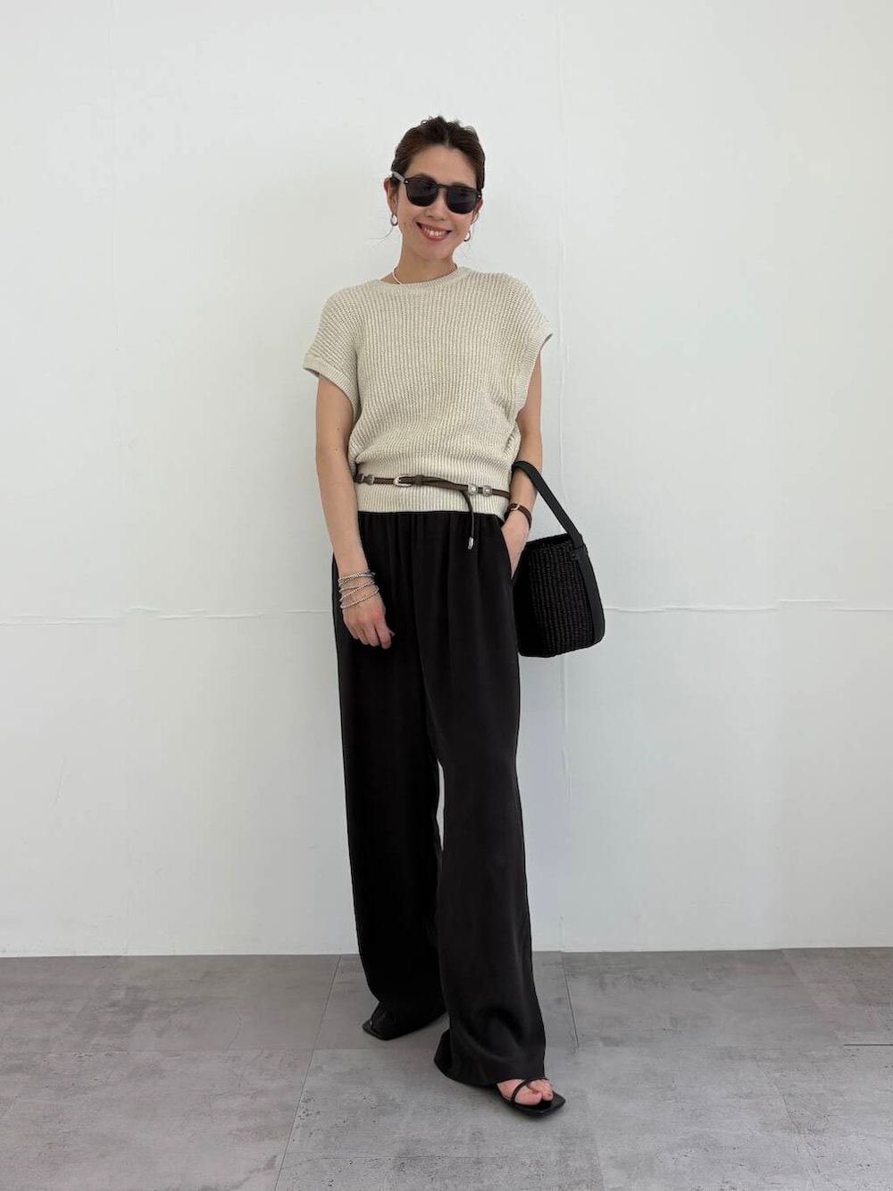 ブラック系のかごバッグ、ブラック系のサンダル、ベージュ系のベストを着用したレディースの夏コーディネートの4枚目の写真