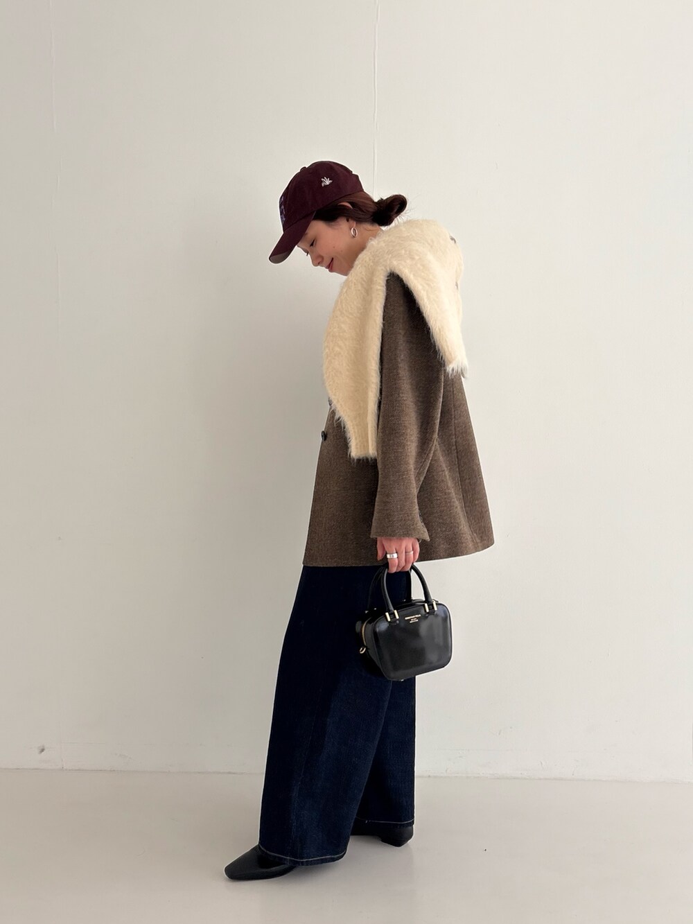 ブルー系のデニムパンツ、ブラック系のローファー、ブラック系のショルダーバッグを着用したレディースの秋コーディネートの3枚目の写真