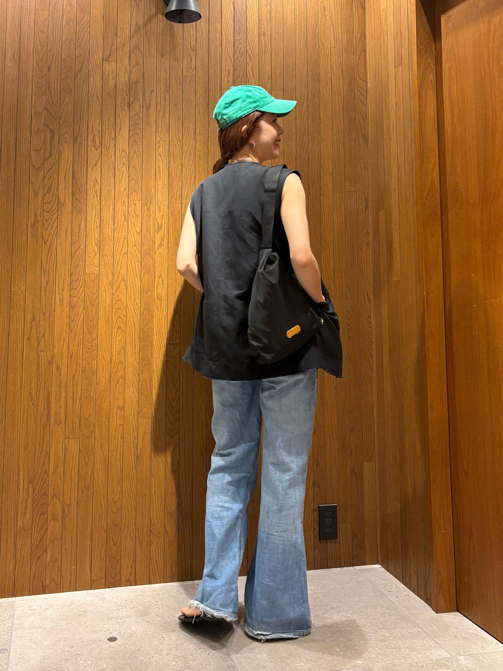 ブラック系のダウンベスト、ブラック系のショルダーバッグ、ホワイト系のTシャツ/カットソーを着用したレディースの夏コーディネートの3枚目の写真