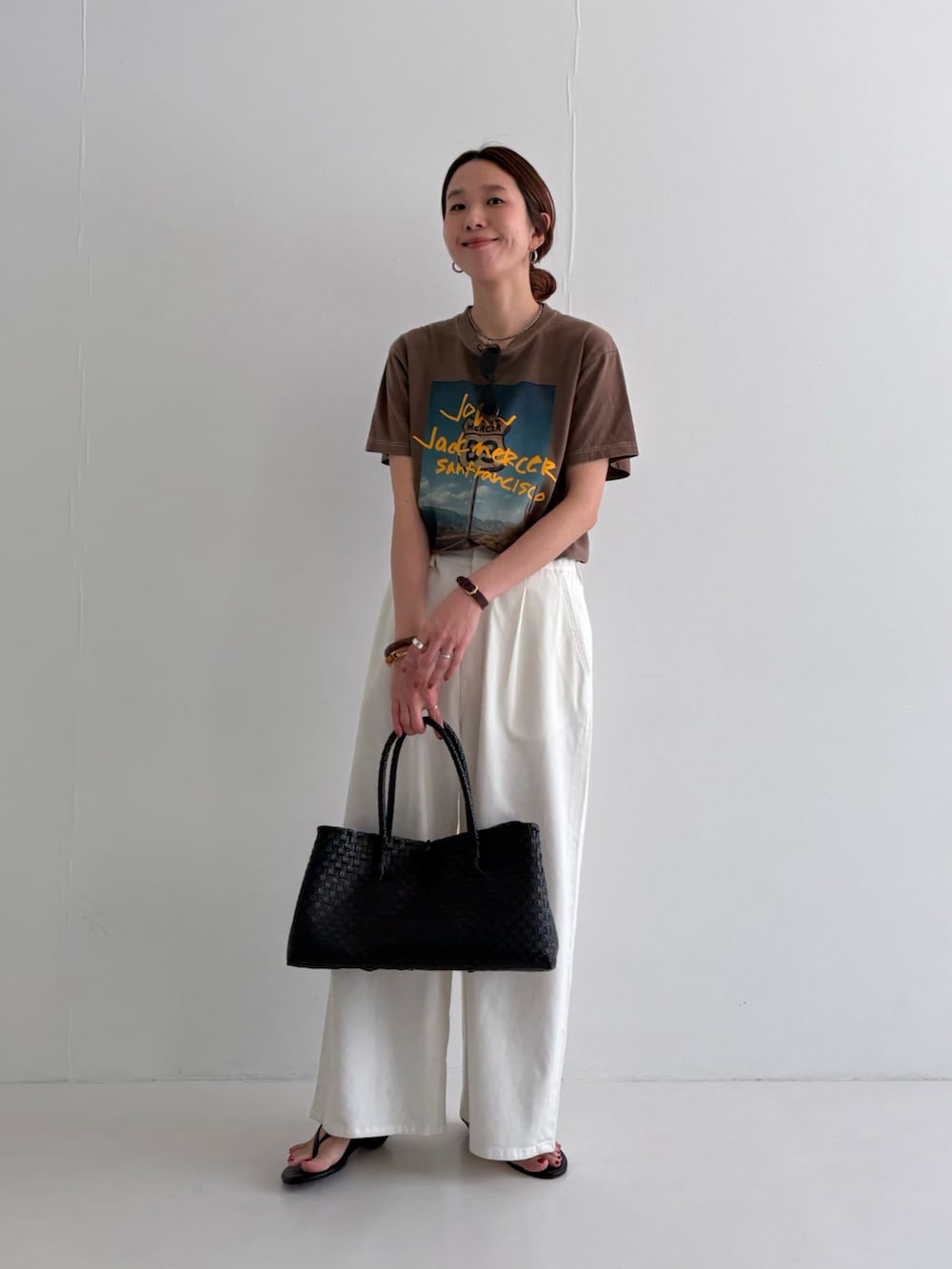 ホワイト系のデニムパンツ、ブラウン系のTシャツ/カットソー、ブラック系のサンダルを着用したレディースの春コーディネートの4枚目の写真
