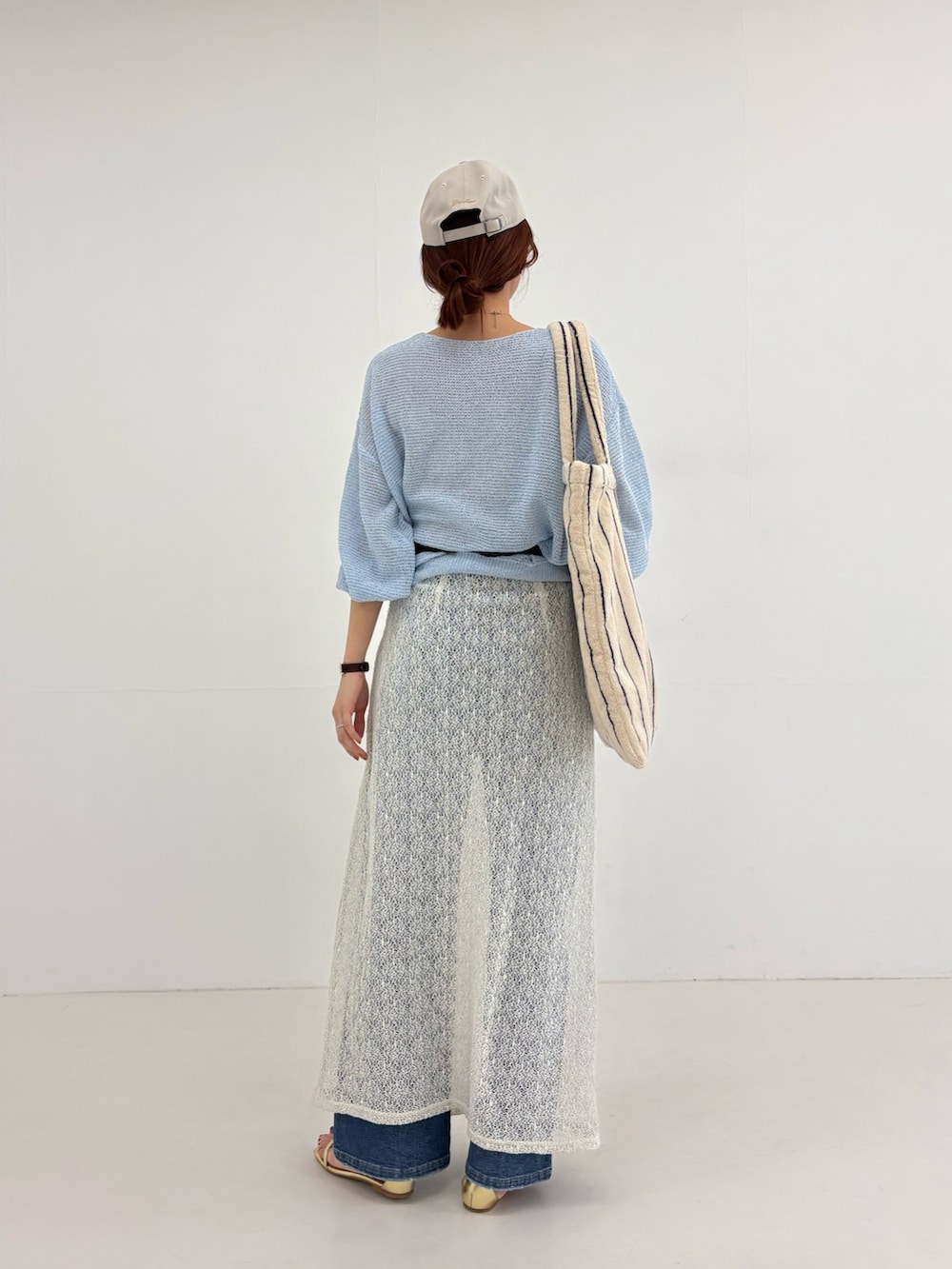 ブルー系のニット/セーター、ホワイト系のスカート、ブラック系のボディバッグ/ウエストポーチを着用したレディースの春コーディネートの4枚目の写真