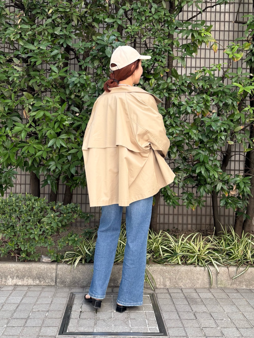 レッド系のシャツ/ブラウス、ベージュ系のトレンチコート、ブルー系のデニムパンツを着用したレディースの春コーディネートの3枚目の写真