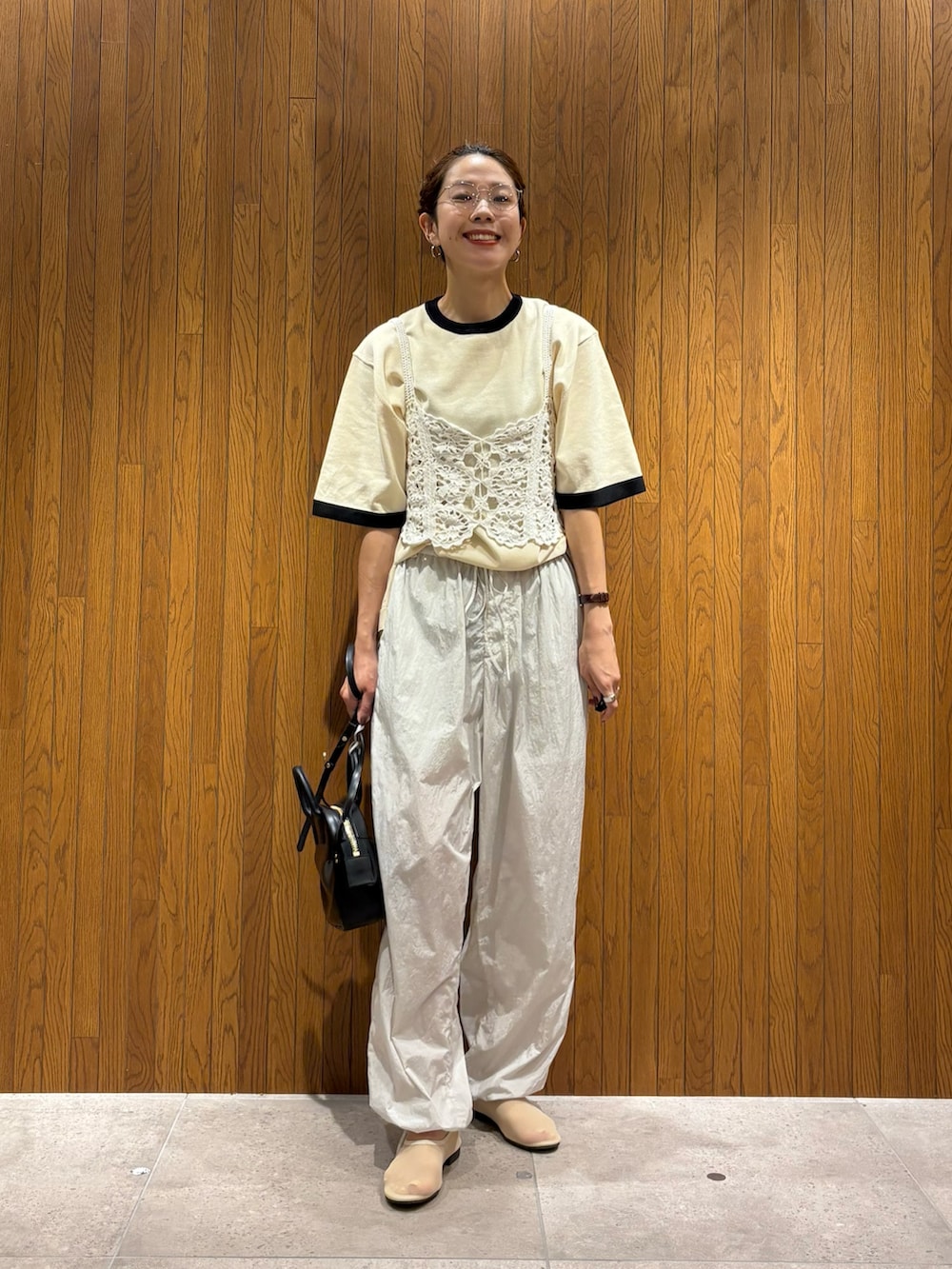 ホワイト系のニット/セーター、グレー系のその他パンツ、ブラック系のショルダーバッグを着用したレディースの夏コーディネートの5枚目の写真