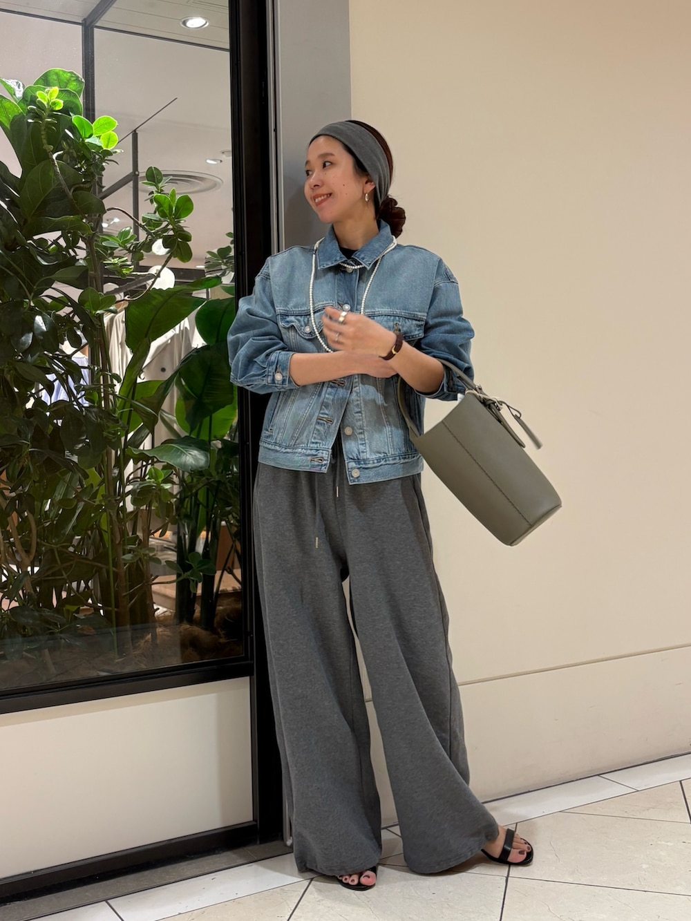 ブルー系のデニムジャケット、グリーン系のハンドバッグ、グレー系のヘアバンドを着用したレディースの春コーディネートの2枚目の写真