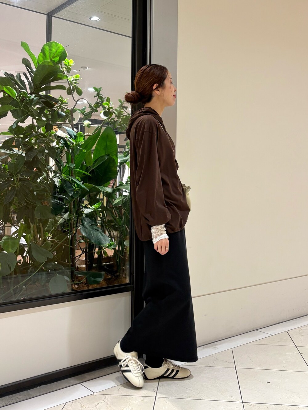 ブラウン系のパーカー、ホワイト系のスニーカー、ブラック系のスカートを着用したレディースの秋コーディネートの2枚目の写真