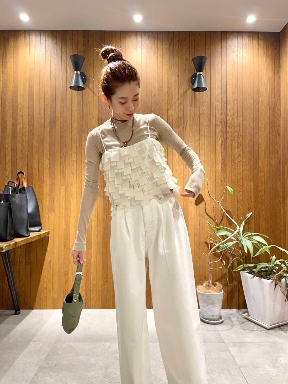 ホワイト系のデニムパンツ、ベージュ系のTシャツ/カットソー、グリーン系のハンドバッグを着用したレディースの冬コーディネートの3枚目の写真