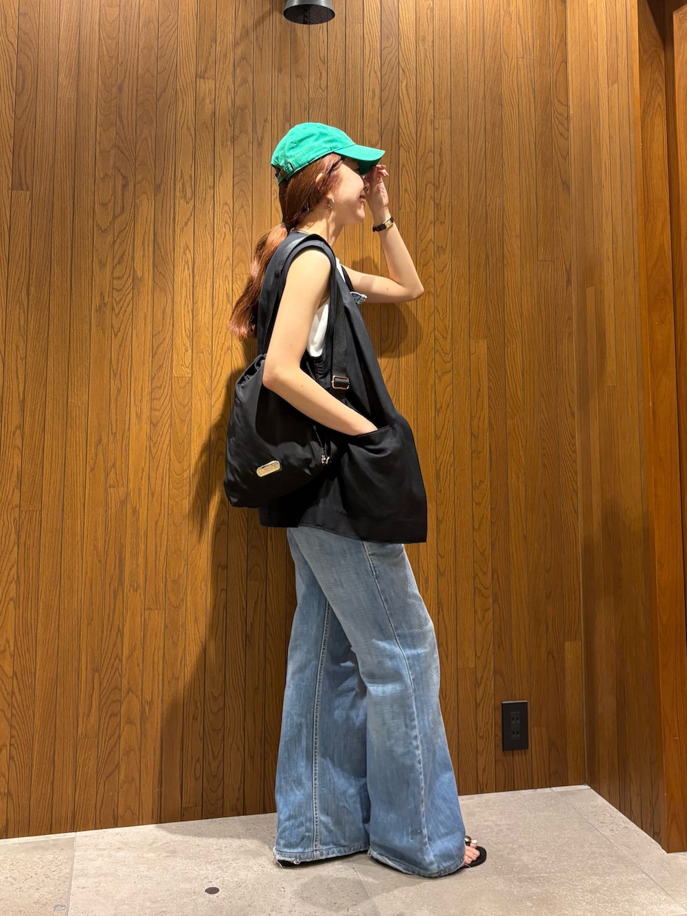 ブラック系のダウンベスト、ブラック系のショルダーバッグ、ホワイト系のTシャツ/カットソーを着用したレディースの夏コーディネートの4枚目の写真