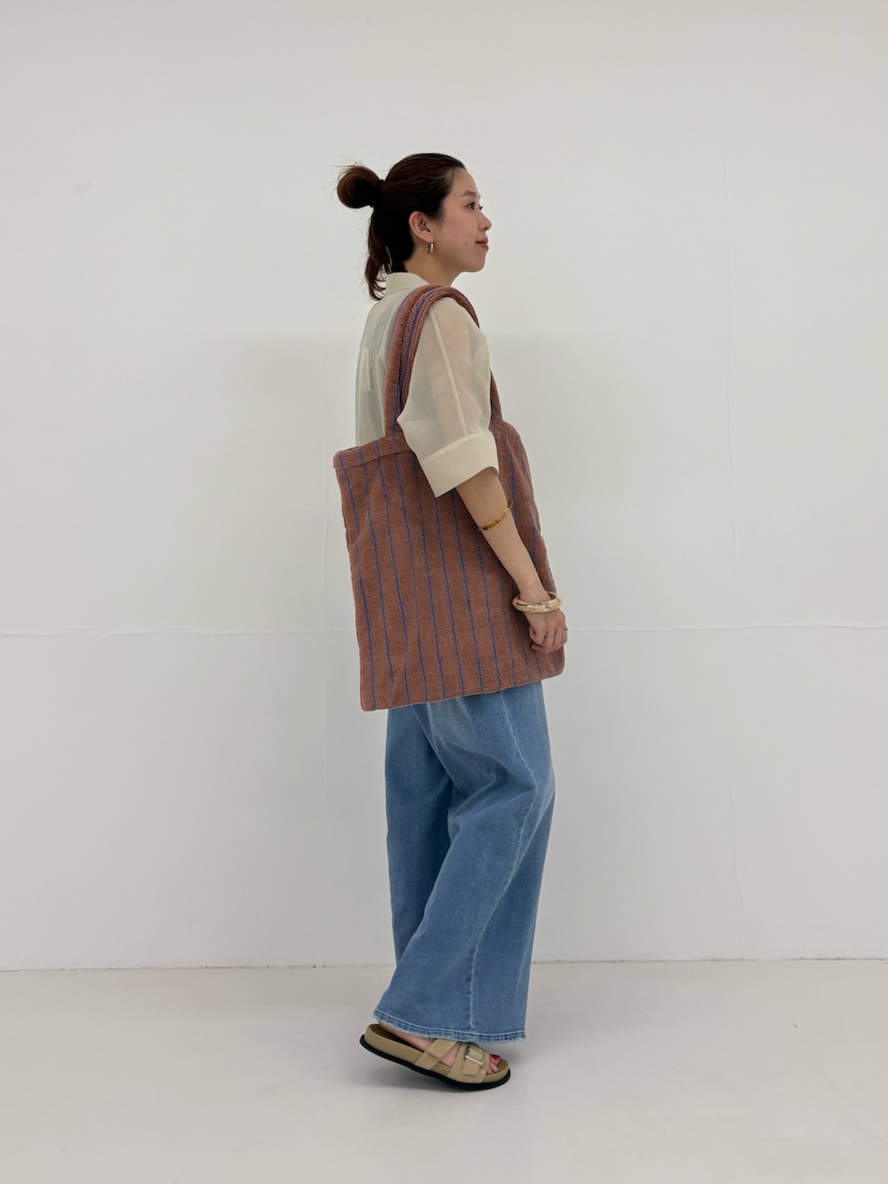 グレー系のシャツ/ブラウス、ブルー系のデニムパンツ、イエロー系のトートバッグを着用したレディースの春コーディネートの2枚目の写真
